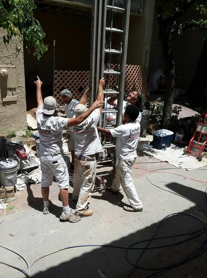 Workers in white uniforms installing a metal door frame at a residential entrance