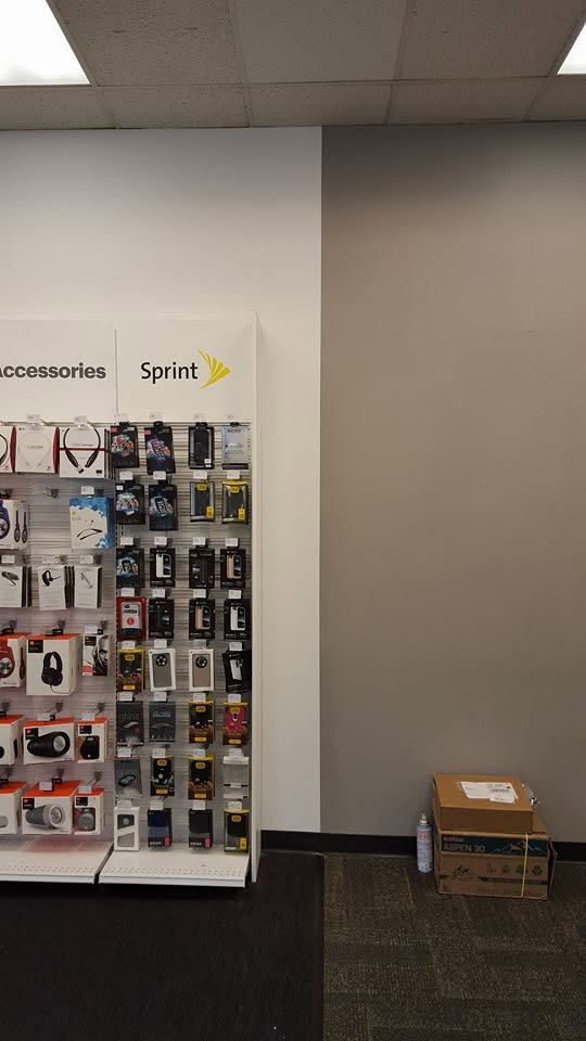 Sprint store display wall with mobile accessories on pegboard and cardboard box on floor