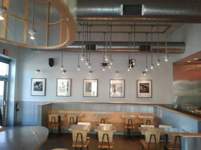Modern restaurant interior with wooden booths, pendant lighting, and framed artwork on walls