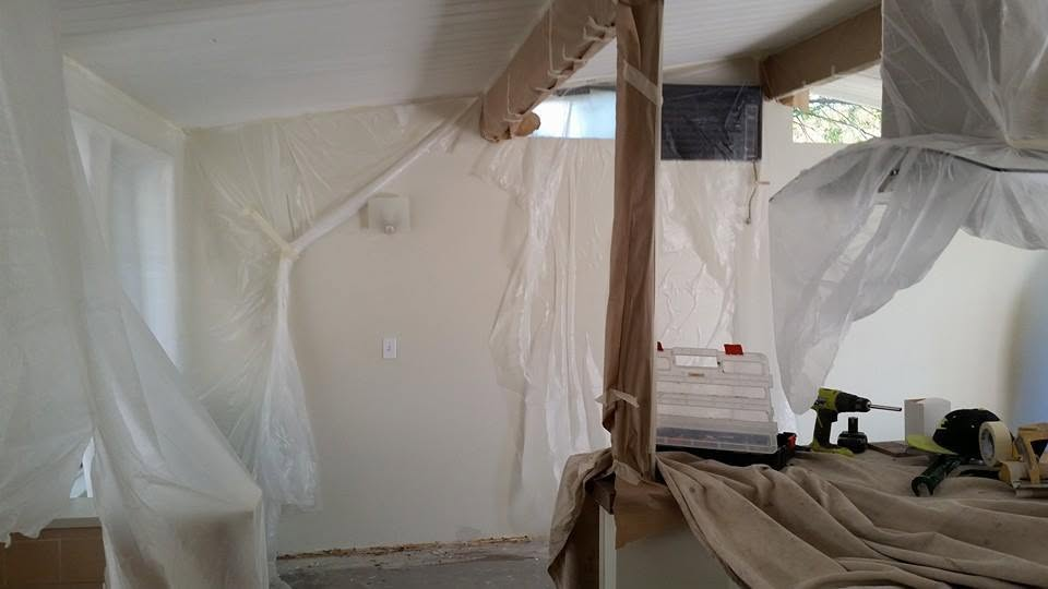Interior room with protective plastic sheeting and construction materials during renovation