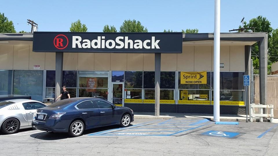 RadioShack storefront with blue car parked in handicapped space and Sprint sign visible