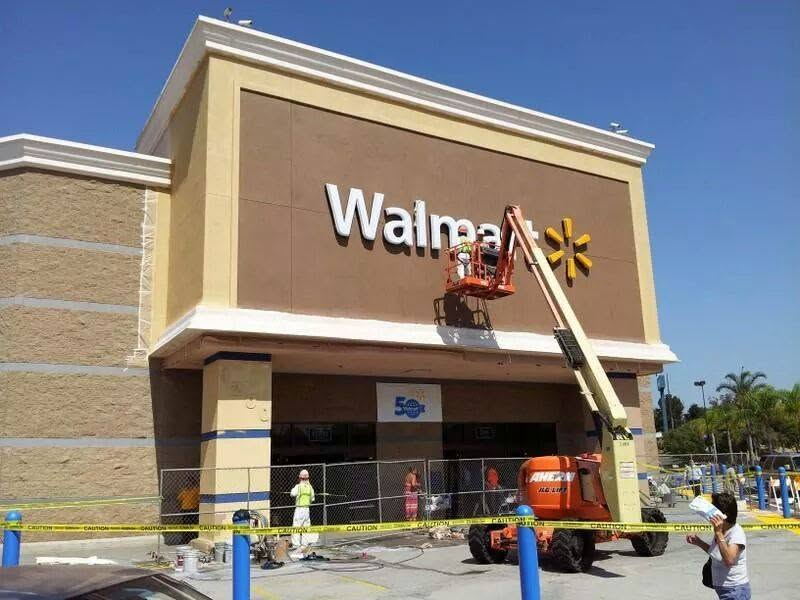 Walmart storefront with workers on lift replacing signage and yellow star logo