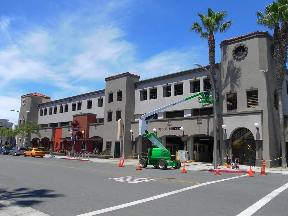 Historic Spanish-style parking structure with clock tower and green aerial lift during maintenance work