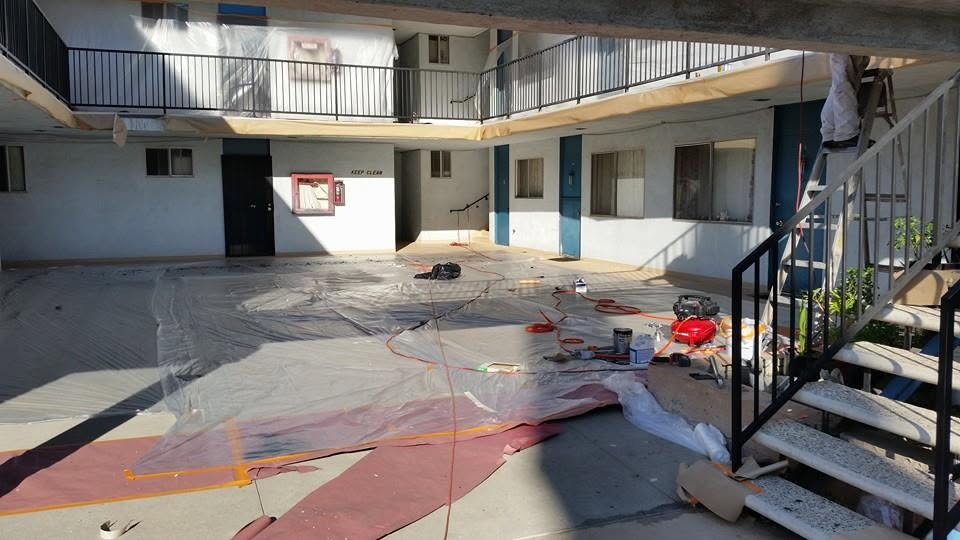 Construction site with protective sheeting, electrical cords, and equipment in courtyard surrounded by white and blue buildings