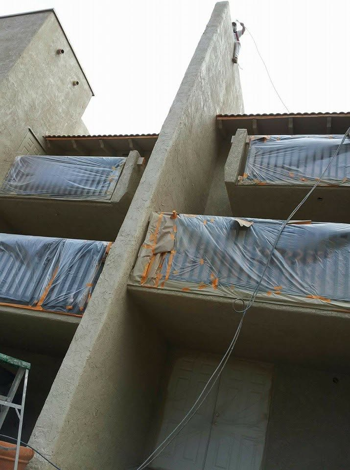 Concrete building under construction with blue plastic sheeting covering multiple floor levels and openings